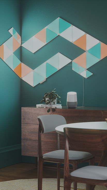 This is an image of Nanoleaf Shapes Triangles and Mini Triangles on a wall inside a dining room. The color changing light panels in this image connect together with linkers and create a design that bends around the corner using flex linkers.