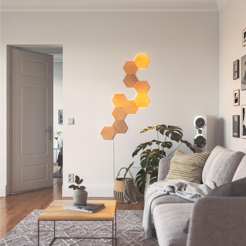 Nanoleaf Elements Thread enabled wood look hexagon smart modular light panels mounted to a wall in a living room. HomeKit, Google Assistant, Amazon Alexa, IFTTT.